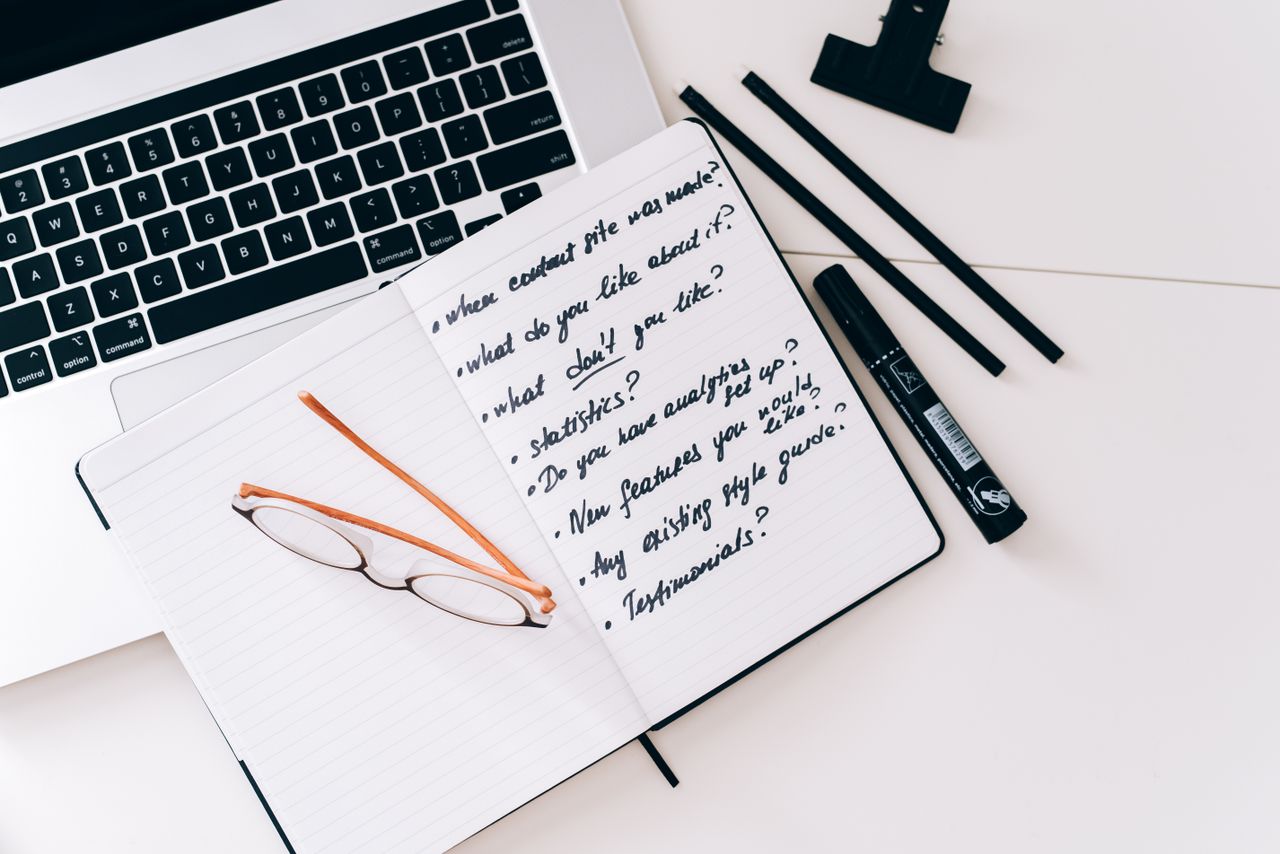 Organized workspace with laptop, notebook, and glasses, perfect for planning and strategy.